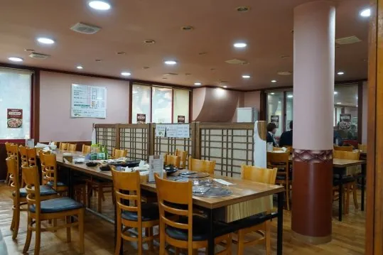 입식 홀 — 나무 탁자와 의자, 창살 칸막이, 벽의 메뉴판